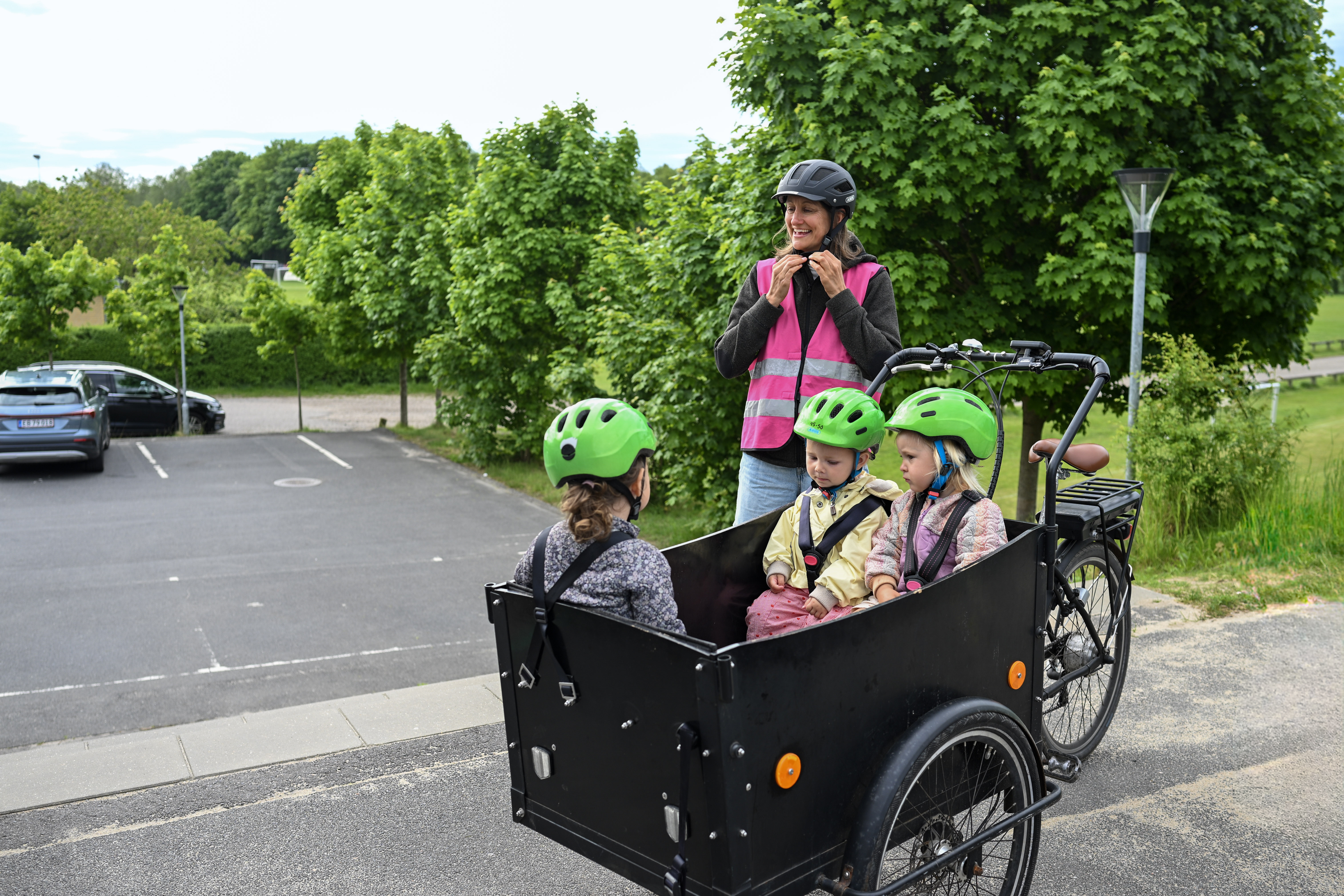 Voksen ved børn i ladcykel