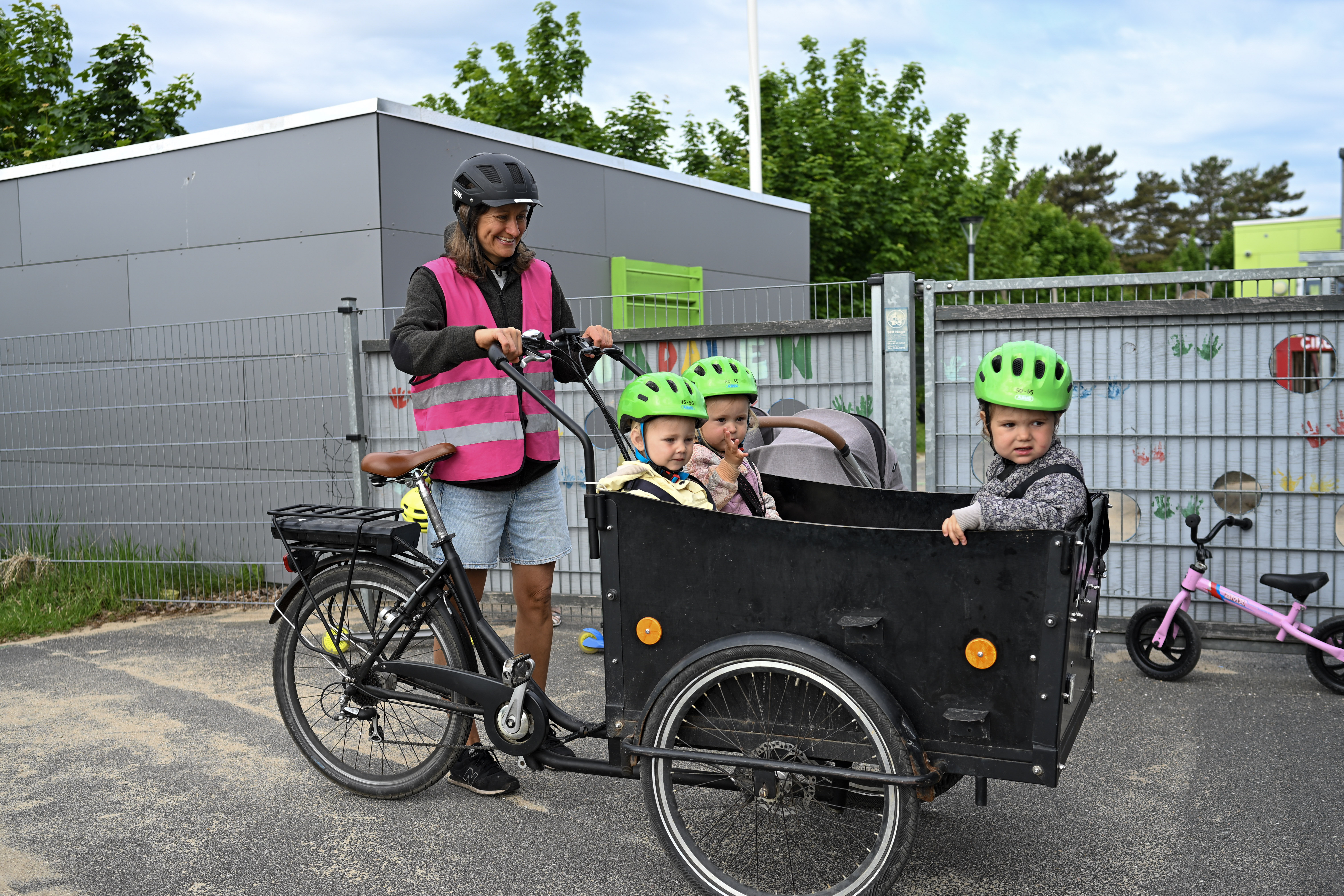 Voksen ved børn i ladcykel