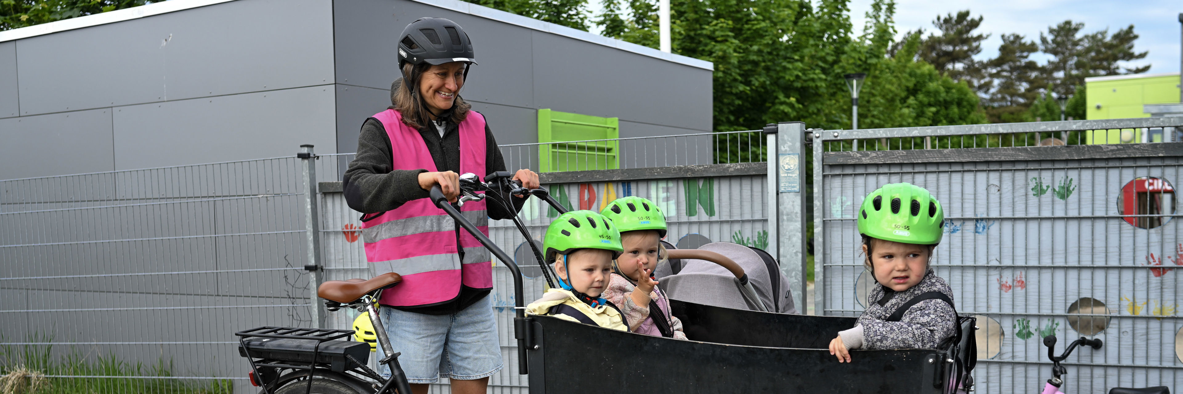 Voksen ved børn i ladcykel